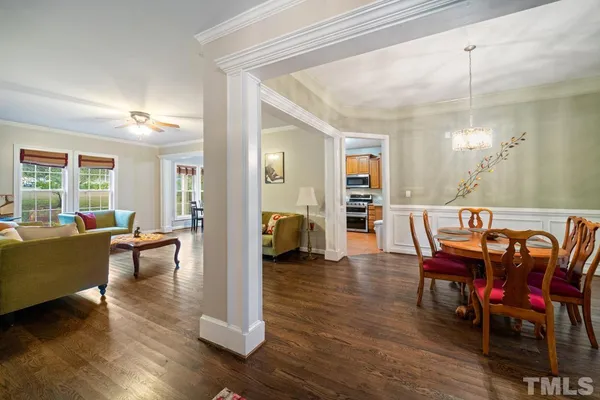 a view of a dining room and livingroom with furniture wooden floor a chandelier