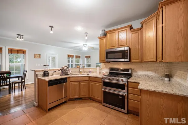 a kitchen with stainless steel appliances granite countertop a stove top oven a sink dishwasher a dining table and chairs with wooden floor