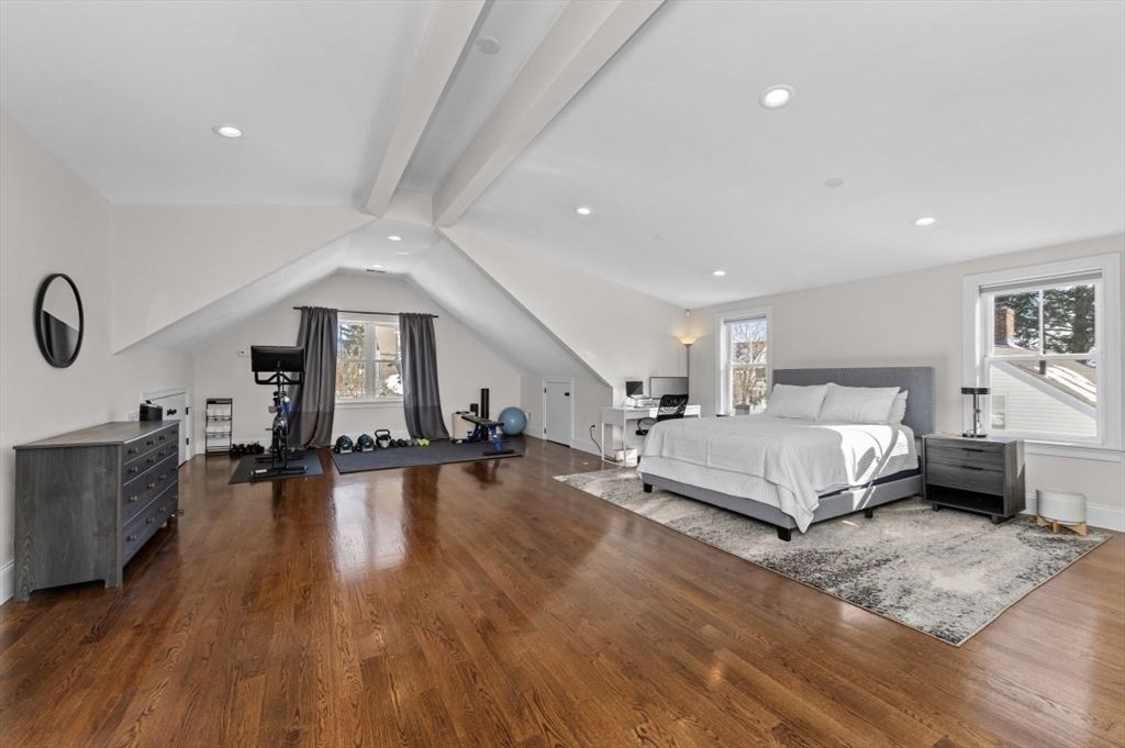 72-74 Manthorne Road, Unit 74 Boston, MA 02132 - Photo 19 of 22 a spacious bedroom with a bed a dresser and wooden floor