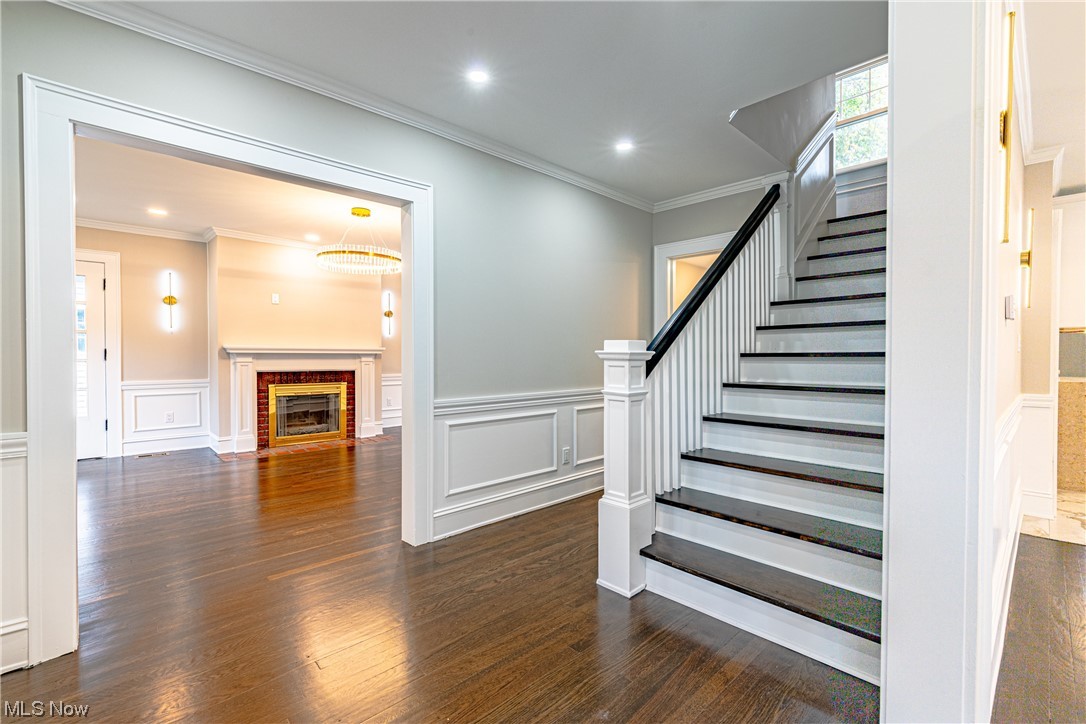 2923 Huntington Road Cleveland, OH 44120 - Photo 3 of 35 Stairs with crown molding, dark wood-type flooring, and a brick fireplace