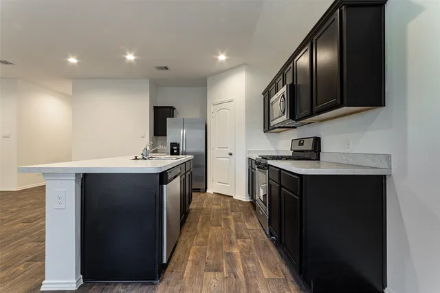 a kitchen with stainless steel appliances granite countertop a stove a sink and a microwave