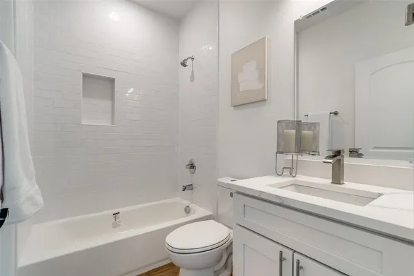 a bathroom with a toilet a sink a mirror a bathtub and vanity
