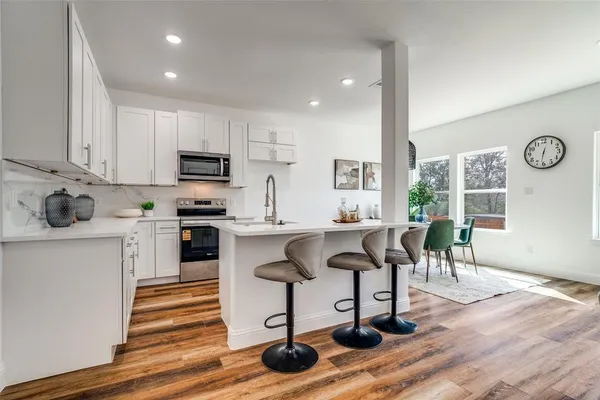 a kitchen with granite countertop a table chairs a sink dishwasher stove and cabinets with wooden floor