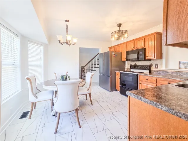 a dining room with wooden floor a chandelier a wooden table and chairs