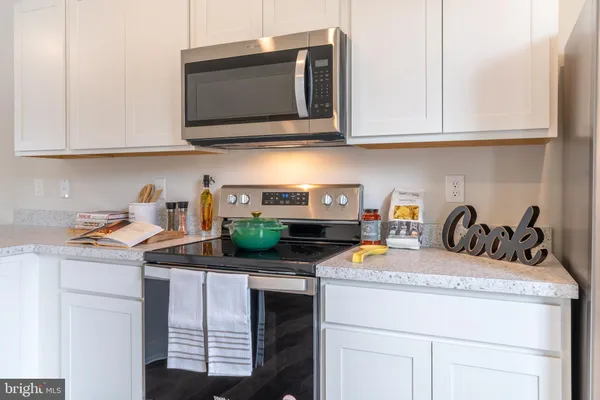 a kitchen with stainless steel appliances granite countertop a sink a stove white cabinets and a wooden floor