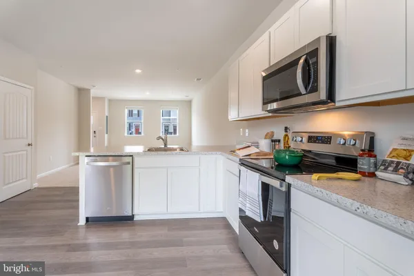 a kitchen with stainless steel appliances granite countertop a stove a sink dishwasher and a microwave with wooden floor