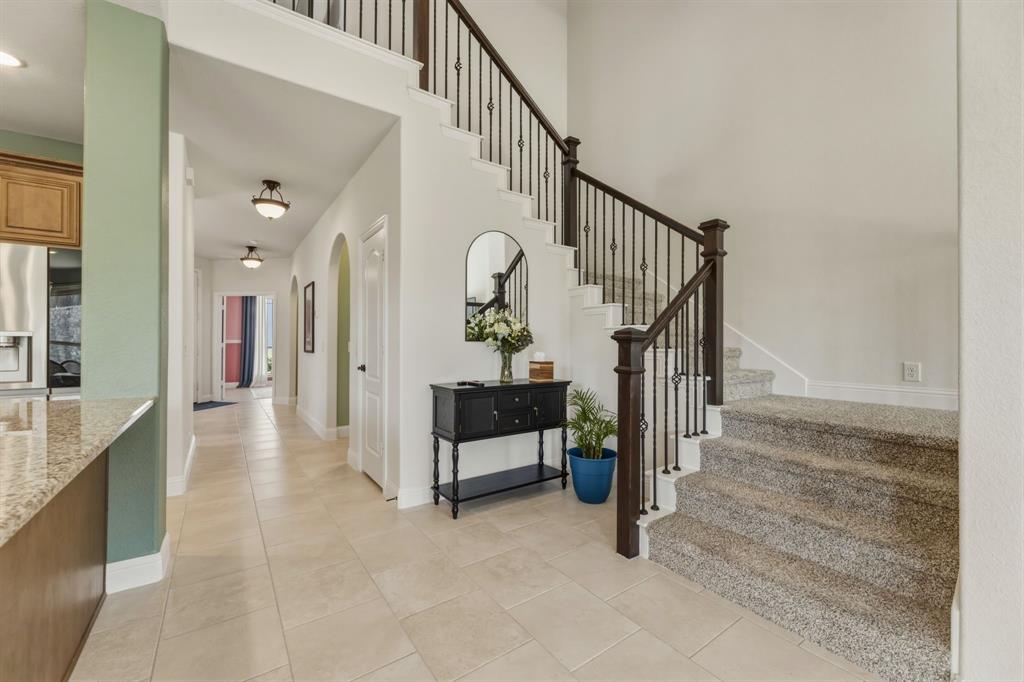 1030 Timber Ridge Drive Justin, TX 76247 - Photo 14 of 40 Stairs featuring tile patterned floors, arched walkways, a high ceiling, and ceiling fan
