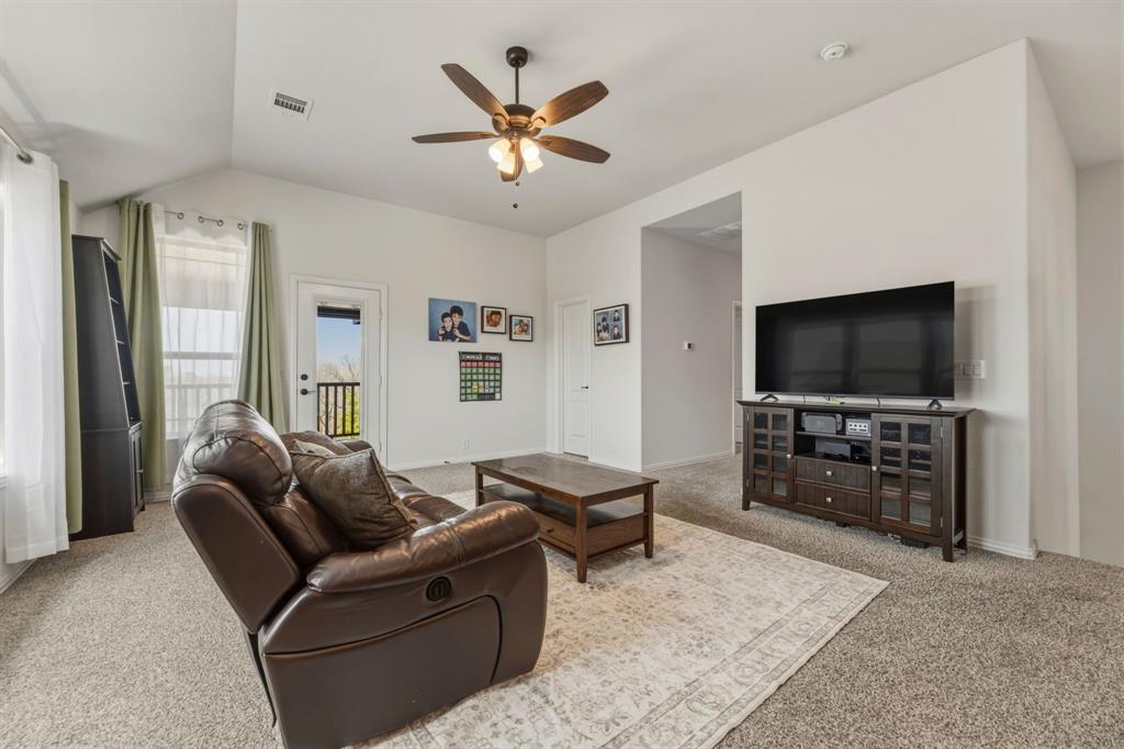 1030 Timber Ridge Drive Justin, TX 76247 - Photo 26 of 40 Living area with light colored carpet, vaulted ceiling, and a ceiling fan