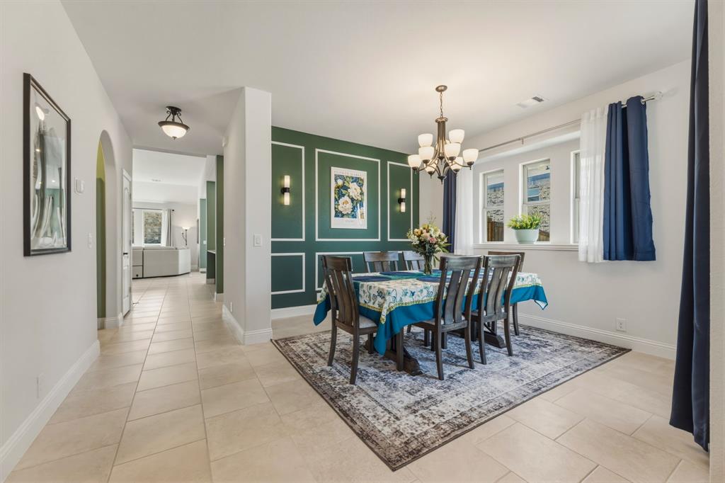 1030 Timber Ridge Drive Justin, TX 76247 - Photo 3 of 40 Dining space featuring light tile patterned flooring, a chandelier, arched walkways, and an accent wall