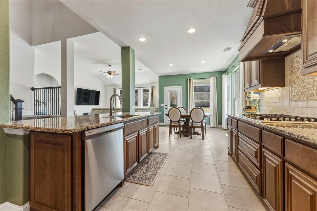 1030 Timber Ridge Drive Justin, TX 76247 - Photo 40 of 40 Kitchen featuring light stone countertops, stainless steel appliances, backsplash, a ceiling fan, and open floor plan