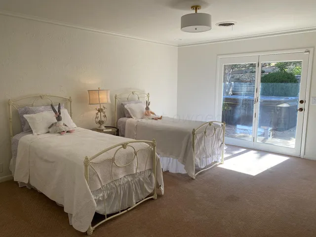 a spacious bedroom with two beds and glass door