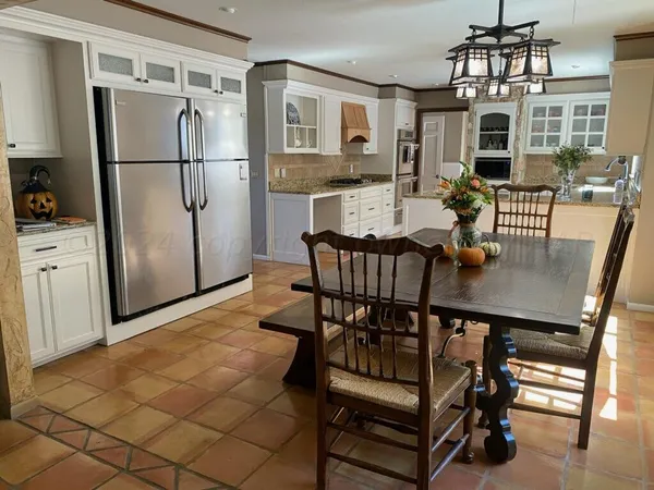 a kitchen with stainless steel appliances a dining table chairs and refrigerator
