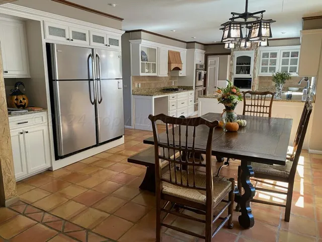a kitchen with stainless steel appliances a dining table chairs and refrigerator