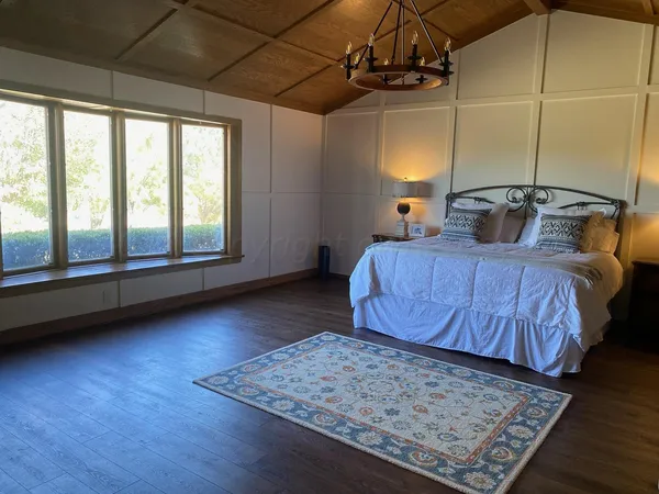 a bedroom with a bed a dresser with wooden floor