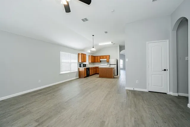 an empty room with kitchen and wooden floor