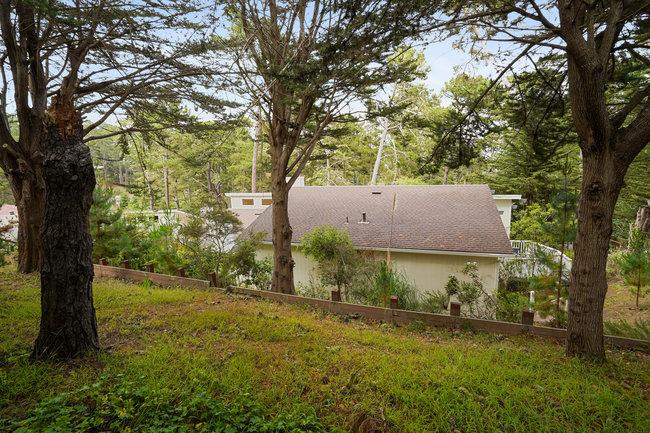 4076 Crest Road Pebble Beach, CA 93953 - Photo 42 of 46 a backyard of a house with large trees and a barn