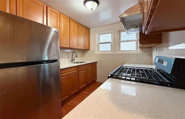 a kitchen with stainless steel appliances granite countertop a refrigerator a sink a stove and a refrigerator