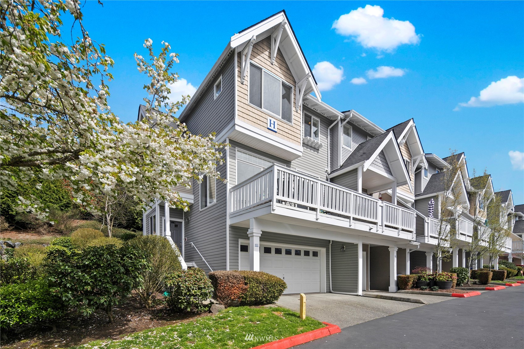a front view of a multi story residential apartment building with yard and parking