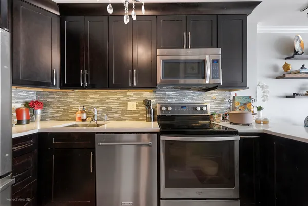 a kitchen with granite countertop stainless steel appliances a sink stove and refrigerator