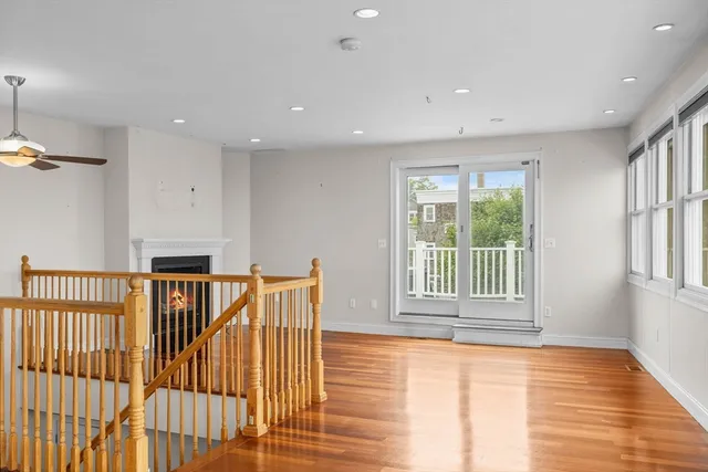 a view of empty room with wooden floor and fan