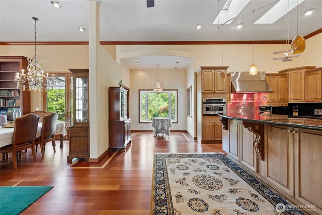 a living room with stainless steel appliances lots of furniture and wooden floors