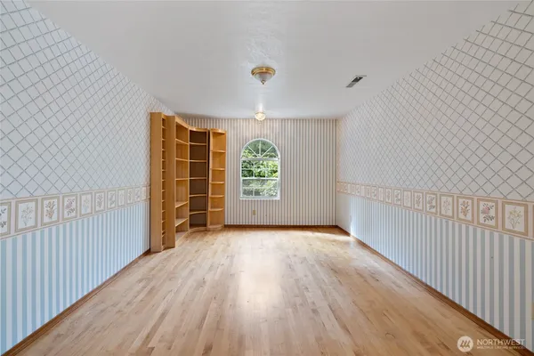 a view of an empty room with window and wooden floor