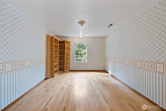 a view of an empty room with window and wooden floor