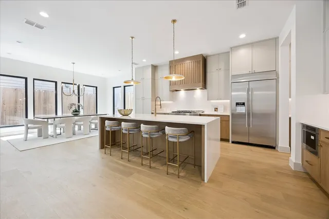 a kitchen with stainless steel appliances kitchen island granite countertop a table chairs and a refrigerator