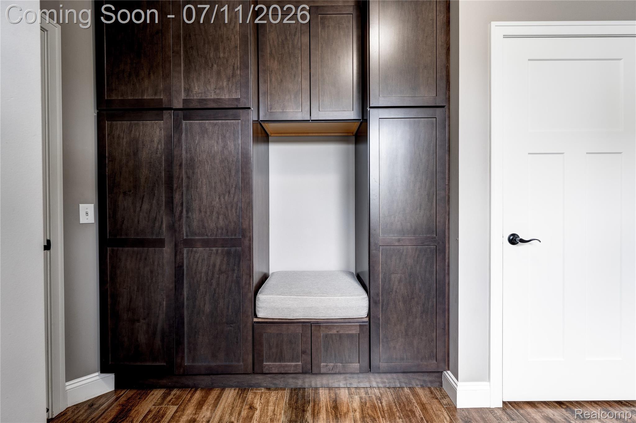 12033 Torrey Road Fenton, MI 48430 - Photo 31 of 51 Built-in cabinetry featuring dark wood-finish doors, a central bench with cushion, open shelving, and integrated storage drawers