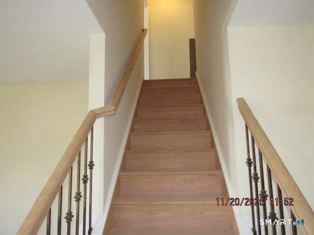 a view of staircase with lots of frames on wall and wooden floor