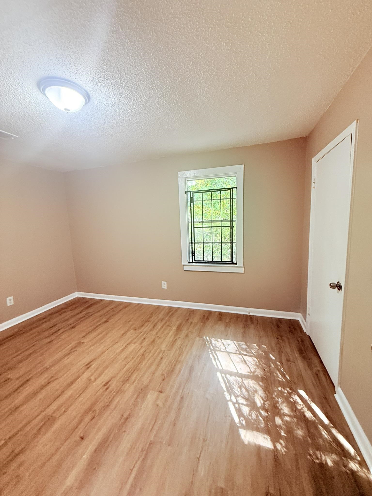 931 Calvin Road Memphis, TN 38109 - Photo 10 of 15 Unfurnished room featuring a textured ceiling and light wood-style flooring