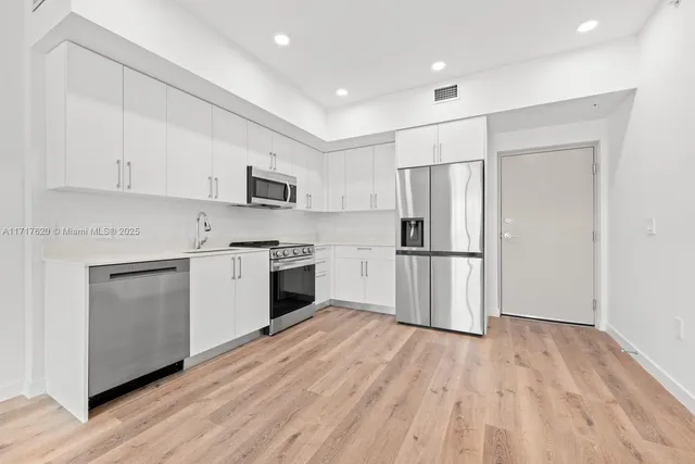 a kitchen with white cabinets and stainless steel appliances