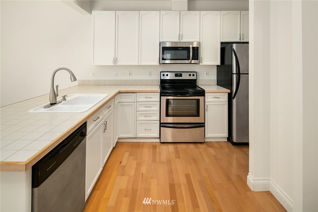 10909 Avondale Road Northeast, Unit F122 Redmond, WA 98052 - Photo 12 of 24 a kitchen with stainless steel appliances a sink dishwasher a refrigerator and a stove top oven