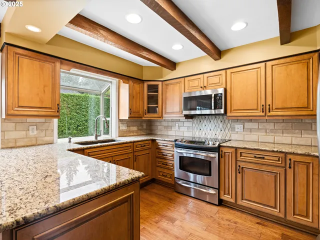 a kitchen with stainless steel appliances granite countertop a stove microwave and sink