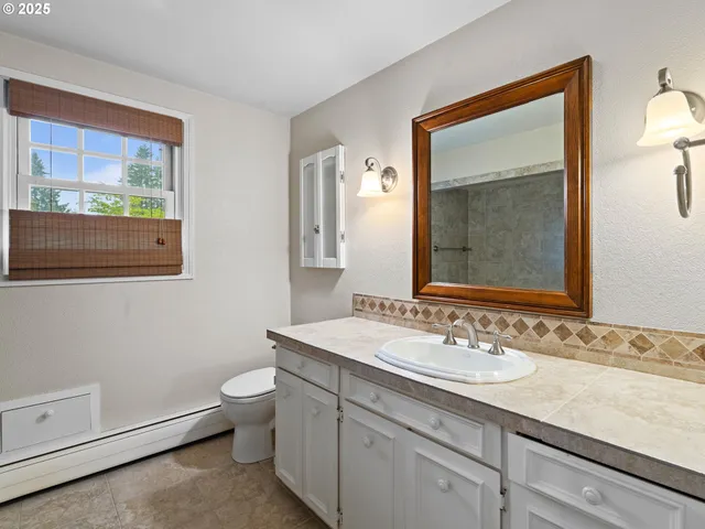 a bathroom with a toilet a sink a mirror and a window