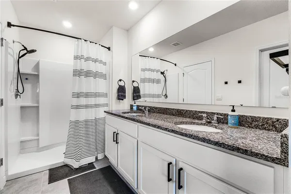 a bathroom with a granite countertop sink a mirror and shower
