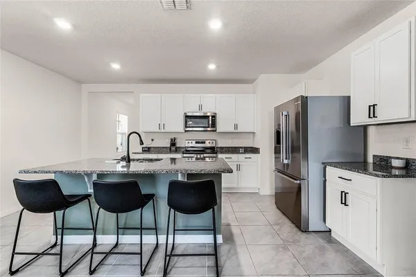 a kitchen with stainless steel appliances granite countertop a sink a stove a refrigerator and cabinets