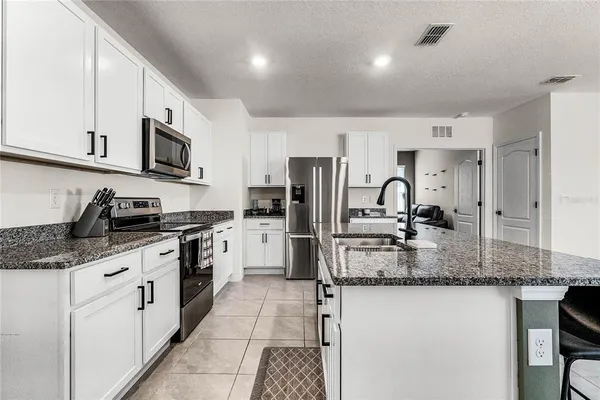 a kitchen with stainless steel appliances granite countertop a sink stove refrigerator and cabinets