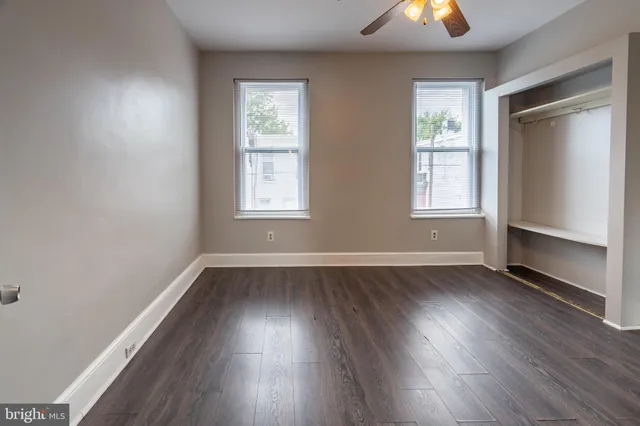 an empty room with wooden floor cabinet and windows
