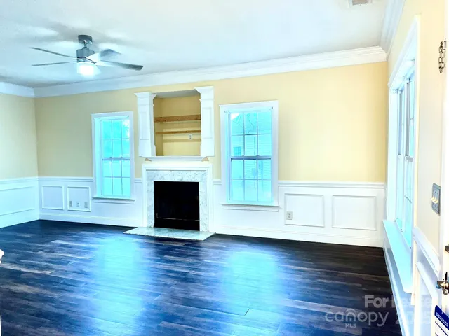 a view of a livingroom with wooden floor a fireplace and windows