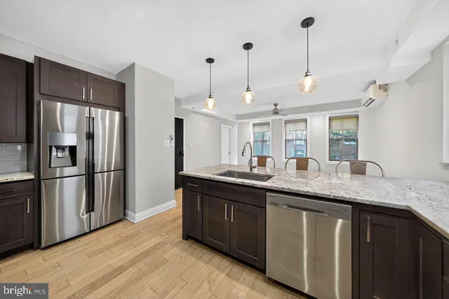 a kitchen with stainless steel appliances granite countertop a sink a refrigerator and a wooden floor