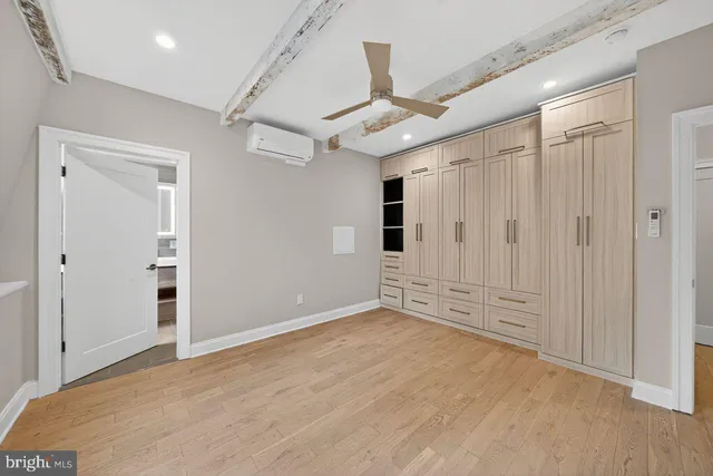 an empty room with wooden floor ceiling fan and windows