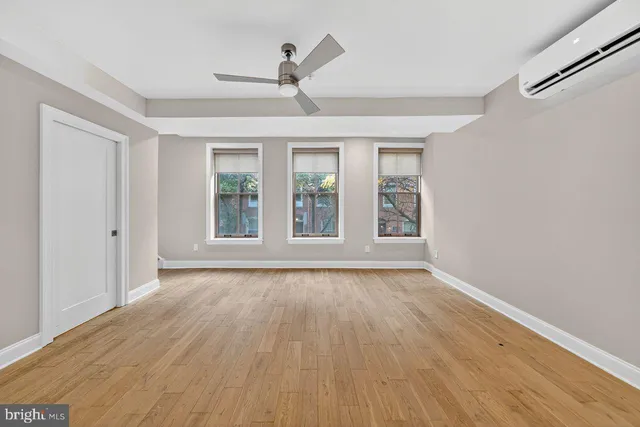a view of an empty room with wooden floor and a window