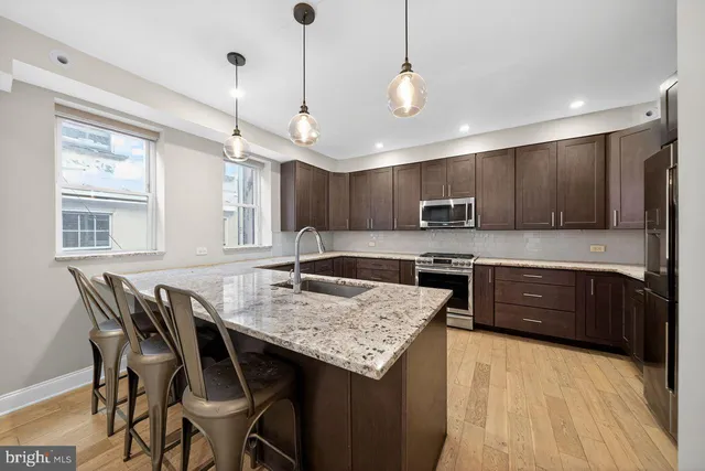 a kitchen with granite countertop a table chairs microwave and cabinets