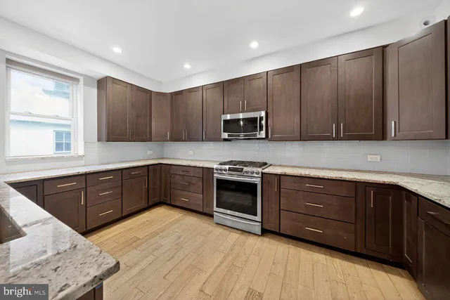 a kitchen with stainless steel appliances granite countertop wooden cabinets a stove top oven a sink and dishwasher