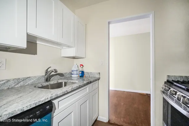 a kitchen with granite countertop a sink dishwasher stove and cabinets