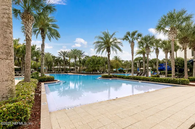 a view of a swimming pool with a patio and palm trees