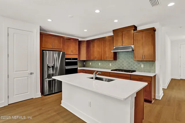 a kitchen with stainless steel appliances granite countertop a refrigerator a sink and a stove