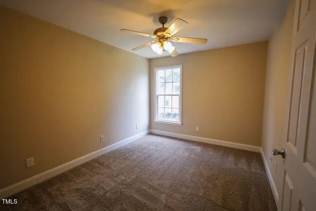 an empty room with windows and chandelier fan
