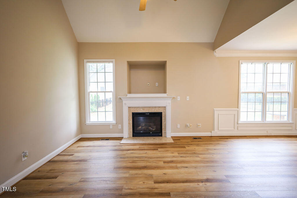 10 London Way Spring Lake, NC 28390 - Photo 4 of 26 an empty room with wooden floor fireplace and windows